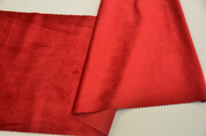 May include: A close-up of a red velvet fabric. The fabric is folded in half and the edges are visible.