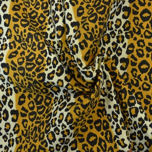 Op de afbeelding: Een close-up van een stof met een luipaardprint. De stof is een mix van wit, zwart en bruin.