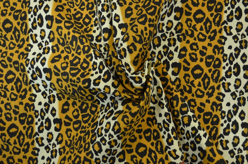 Op de afbeelding: Een close-up van een stof met een luipaardprint. De stof is een mix van wit, zwart en bruin.