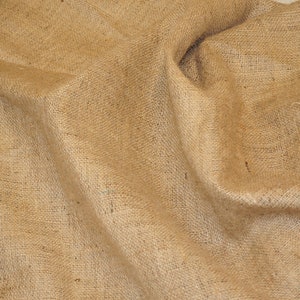 May include: A close-up of a natural brown burlap fabric with a rough texture. The fabric is folded and wrinkled, creating a rustic and organic look.