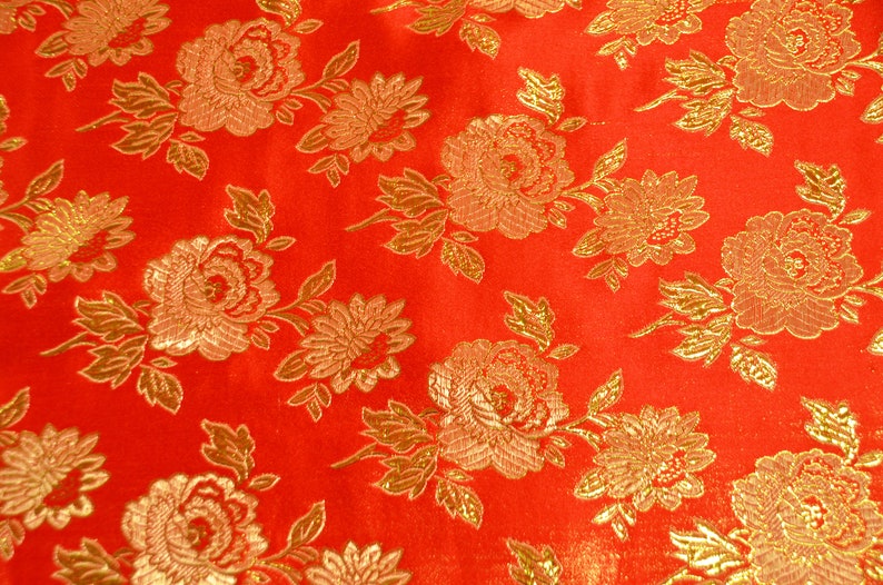 May include: Red fabric with a gold floral pattern. The fabric has a shiny, satin-like finish.