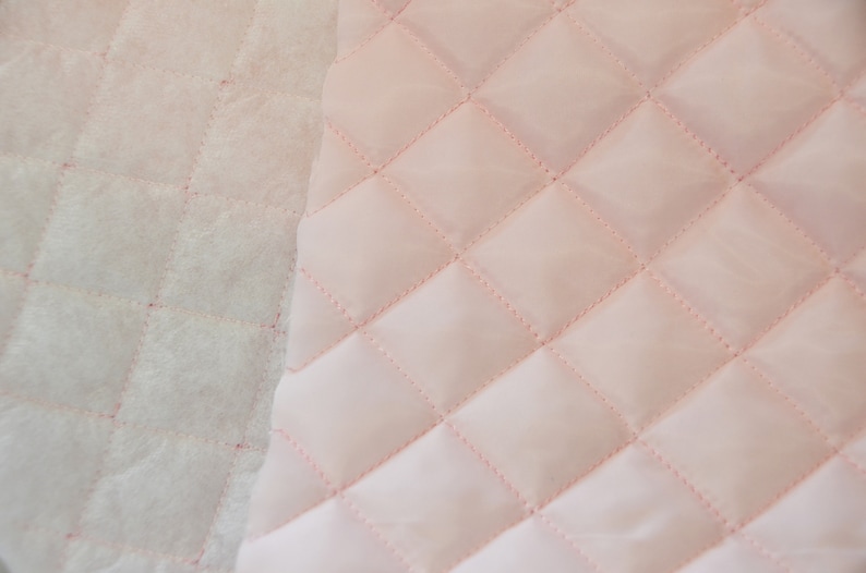 May include: Close-up of two quilted fabrics, one white and one pink. Both fabrics have a diamond pattern.