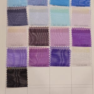 May include: A color chart of sheer fabric swatches in various shades of blue, purple, and silver. The swatches are arranged in a grid with the color names printed below each swatch.