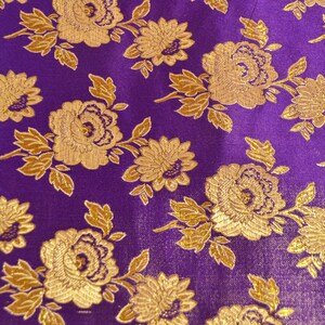 May include: Purple fabric with a gold floral pattern. The fabric has a textured, brocade-like appearance.