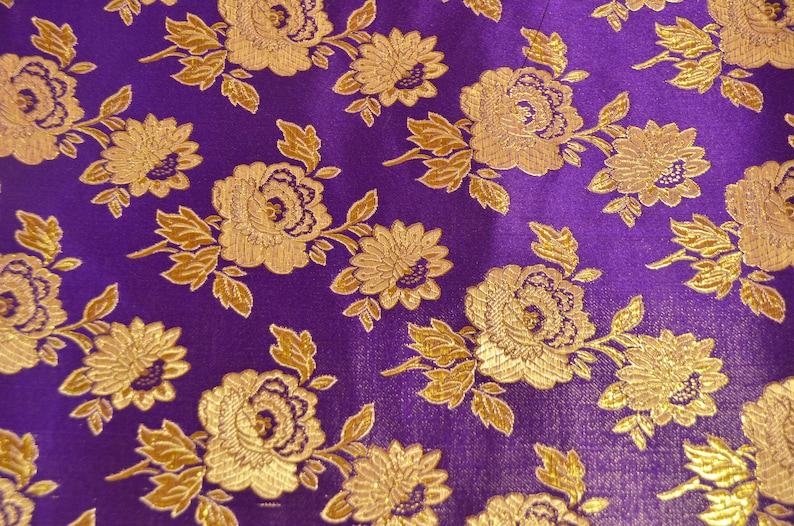May include: Purple fabric with a gold floral pattern. The fabric has a textured, brocade-like appearance.