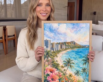 May include: A framed watercolor painting depicting a tropical coastal scene with Diamond Head crater in the background, a sandy beach, blue ocean water, palm trees, and large pink hibiscus flowers in the foreground, all set in a light wood frame.