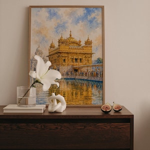 Può includere: Un dipinto ad acquerello incorniciato del Tempio d'Oro di Amritsar, in India, con una struttura dorata riflessa nell'acqua sotto un cielo blu e bianco. Un giglio bianco in un vaso di vetro, una scultura a nodo bianca e due metà di fico.