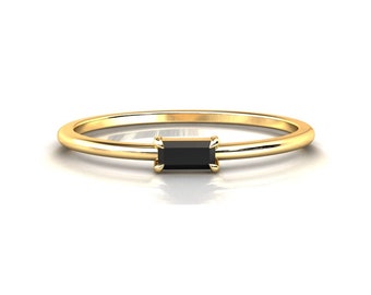 May include: A gold band ring with a black rectangular gemstone.