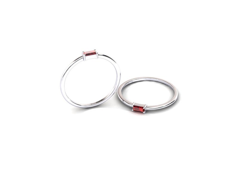 May include: Two silver rings with a small, rectangular, red gemstone set in the band.