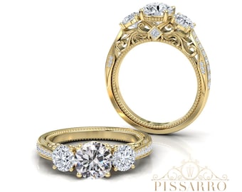 May include: A three-stone engagement ring with a gold band and intricate filigree detailing. The ring features a large, round center stone flanked by two smaller stones. The band is adorned with small accent stones.