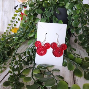 May include: Red rhinestone Mickey Mouse earrings with silver hooks. The earrings are displayed on a white card.