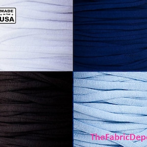 May include: Four spools of fabric in different colors: white, navy blue, black, and light blue. The spools are stacked on top of each other. The text "Made in the USA" is visible in the top left corner of the image.