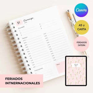 May include: A white spiral-bound daily planner page with black text including 'Domingo', 'Enero', 'Prioridades', 'Horarios', and 'Notas'. A silver pen rests beside it. A digital tablet displays a pink cover with white daisy patterns and 'Agenda 2027'.