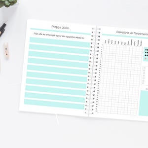 Pode incluir: Caderno aberto com encaderna&ccedil;&atilde;o em espiral, com linhas horizontais azuis claras na p&aacute;gina esquerda e uma grade de calend&aacute;rio na direita. O texto em espanhol inclui "Metas 2026" e "Calendario de menstruaci&oacute;n."