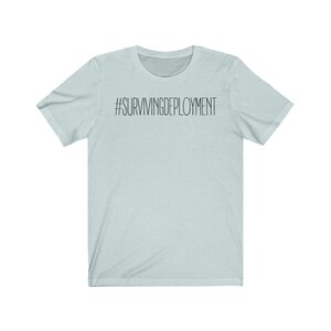 May include: A light blue t-shirt with the text "#SURVIVINGDEPLOYMENT" printed in black on the front.