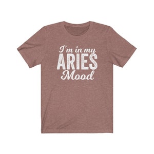 以下が含まれることがあります： ヘザーブラウンのTシャツに「I'm in my ARIES Mood」という白い文字が書かれています。