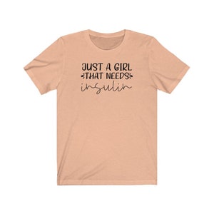 May include: A peach-colored t-shirt with the text "Just a girl that needs insulin" in black.