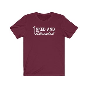 May include: Burgundy short-sleeved t-shirt with white text that reads "INKED AND Educated".