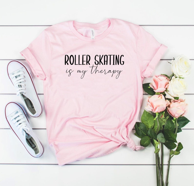 May include: Pink t-shirt with the text "Roller Skating is my therapy" in black lettering.