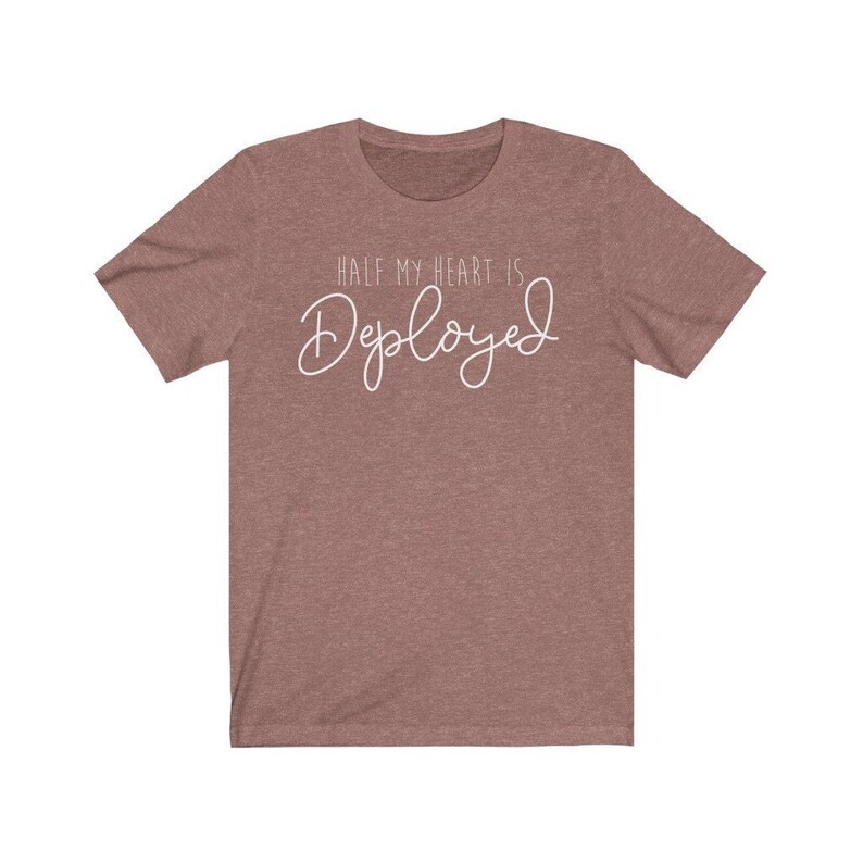 May include: A heather brown t-shirt with the text "Half my heart is Deployed" in white cursive lettering.