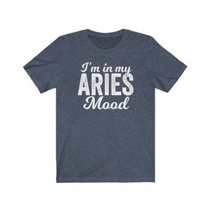 以下が含まれることがあります： 白い文字で「I'm in my ARIES Mood」と書かれた濃い青色のTシャツです。