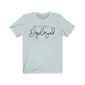 May include: A light blue t-shirt with the text "HALF MY HEART IS Deployed" in black.