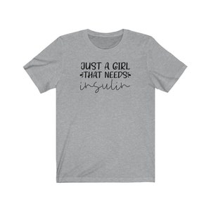 May include: Gray short-sleeved t-shirt with the text "Just a girl that needs insulin" in black.