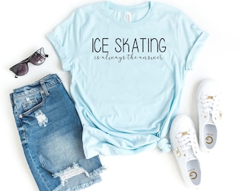 May include: A light blue t-shirt with the text "ICE SKATING is always the answer" in black lettering. The shirt is laid out on a white surface with a pair of sunglasses, denim shorts, and white sneakers.