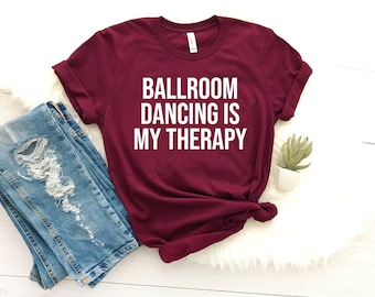 May include: Burgundy t-shirt with white text that reads "Ballroom Dancing is My Therapy".