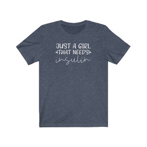 May include: A dark blue t-shirt with the text "Just a girl that needs insulin" in white.