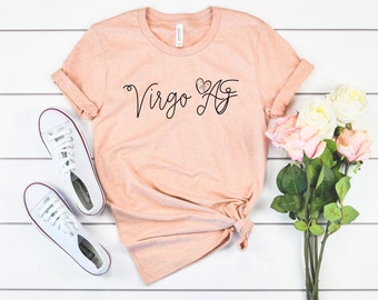 以下が含まれることがあります： 桃色のTシャツに、黒い筆記体で「Virgo AF」という文字が書かれており、「F」の上に小さなハートがあります。