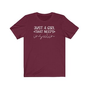 May include: Burgundy short-sleeved t-shirt with white text that reads "Just a girl that needs insulin".