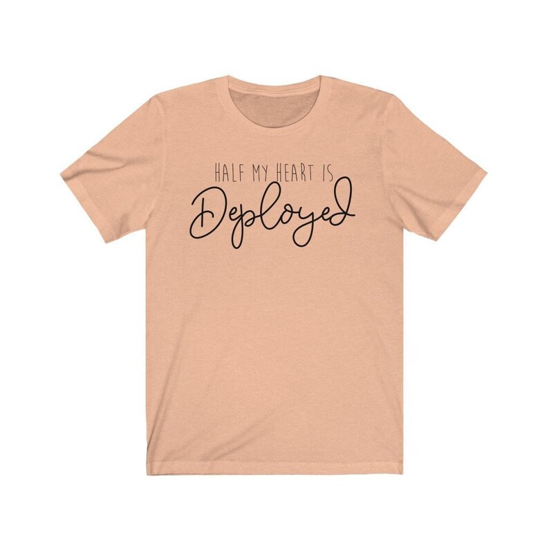 May include: Peach-colored t-shirt with the text "Half my heart is Deployed" in black script.
