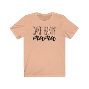 May include: A peach-colored t-shirt with the text "CAKE BAKIN' mama" printed in black.