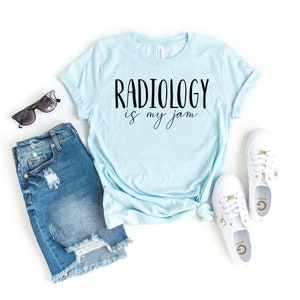 May include: Light blue t-shirt with the text "Radiology is my jam" in black lettering.