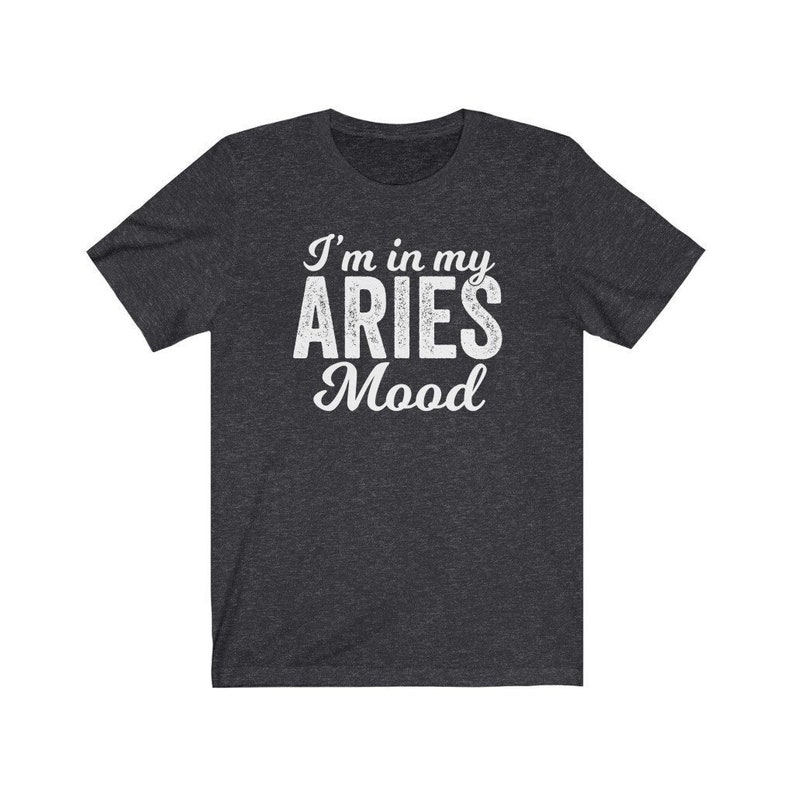 以下が含まれることがあります： 暗いヘザーグレーのTシャツに、白い文字で「I'm in my Aries Mood」と書かれています。