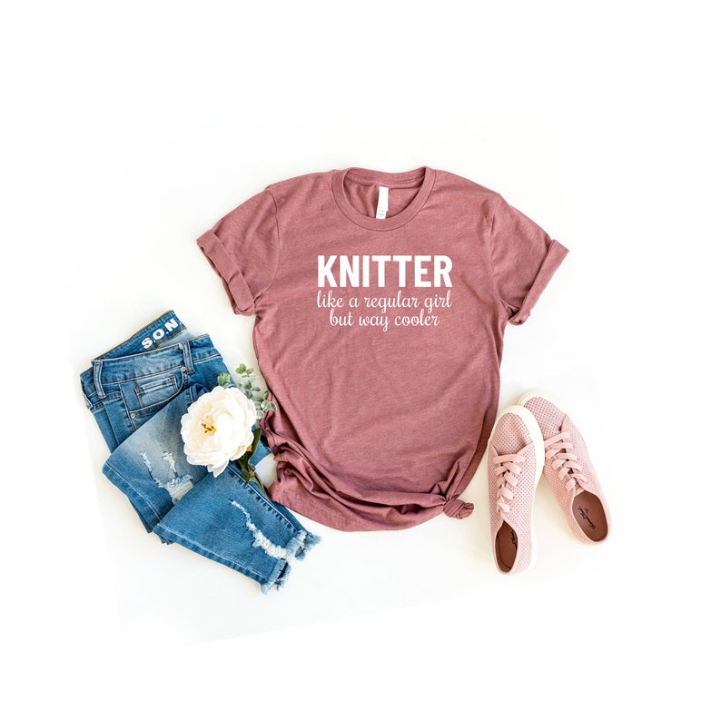 Puede incluir: Una camiseta color malva con el texto "KNITTER like a regular girl but way cooler" en blanco.