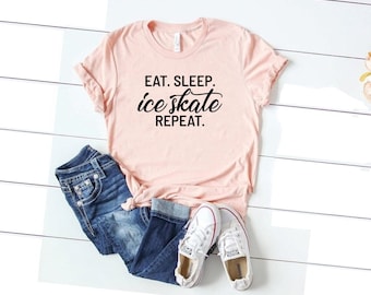 May include: A pink t-shirt with the text "Eat. Sleep. ice skate. Repeat." in black lettering.
