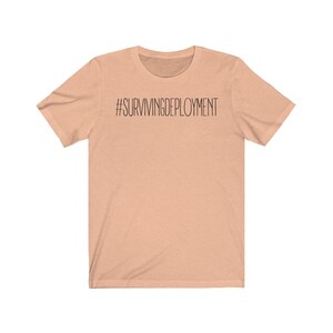 May include: A peach-colored t-shirt with the text "#SURVIVINGDEPLOYMENT" printed in black.
