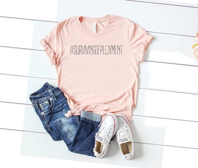 May include: A pink t-shirt with the text "#SURVIVINGDEPLOYMENT" printed in black.