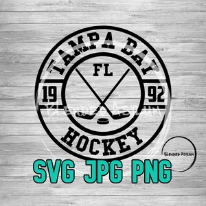 May include: Black and white graphic of a hockey stick and puck inside a circle with the text "Tampa Bay FL 1992 Hockey" around the outside. The text "SVG JPG PNG" is below the circle.