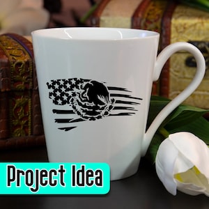 Pode incluir: Caneca de cer&acirc;mica branca com um design em preto e branco de uma bandeira americana com uma &aacute;guia mexicana e um cacto dentro da bandeira. O texto "Project Idea" est&aacute; impresso em turquesa sobre um fundo branco.