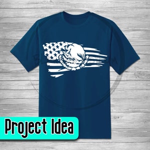 Pode incluir: Uma camiseta azul marinho com um design de bandeira americana branca desbotada que apresenta uma &aacute;guia branca com uma coroa. A &aacute;guia est&aacute; centrada na bandeira e a bandeira est&aacute; inclinada diagonalmente sobre a camiseta.