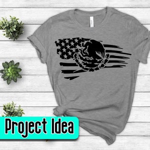 Pode incluir: Camiseta cinza com um design de bandeira americana desbotada em preto e branco que apresenta o bras&atilde;o de armas mexicano. "Project Idea" est&aacute; escrito em turquesa sobre um ret&acirc;ngulo branco.