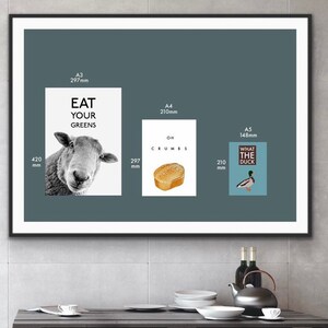 May include: Three framed prints with humorous text and illustrations. The first print is A3 size (297mm x 420mm) and features a black and white illustration of a sheep with the text "Eat Your Greens". The second print is A4 size (210mm x 297mm) and features a cartoon illustration of a slice of bread with the text "Oh Crumbs". The third print is A5 size (148mm x 210mm) and features a cartoon illustration of a duck with the text "What The Duck".