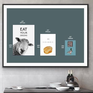 May include: Three framed prints with humorous text and illustrations. The first print is A3 size (297mm x 420mm) and features a black and white illustration of a sheep with the text "Eat Your Greens". The second print is A4 size (210mm x 297mm) and features a cartoon illustration of a slice of bread with the text "Oh Crumbs". The third print is A5 size (148mm x 210mm) and features a cartoon illustration of a duck with the text "What The Duck".