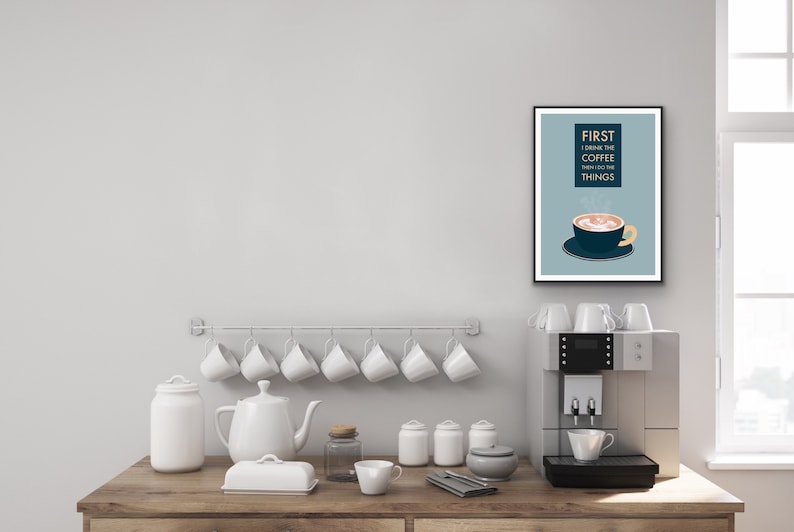 May include: A framed print with a blue background and white text that reads "FIRST I DRINK THE COFFEE THEN I DO THE THINGS". A cartoon illustration of a coffee cup with steam rising from it is below the text.