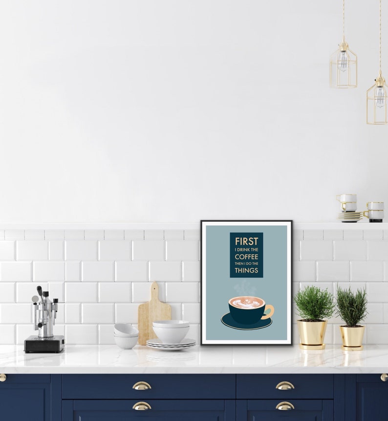 May include: A blue and white framed print with the text "FIRST I DRINK THE COFFEE THEN I DO THE THINGS" and a cartoon illustration of a steaming cup of coffee.