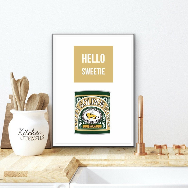 May include: A white framed print with a gold background and the text "HELLO SWEETIE" in white. Below the text is a green and gold illustration of a Lyle's Golden Syrup can.