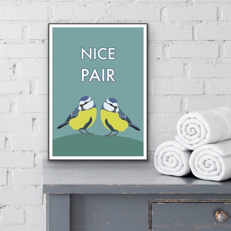 May include: A teal blue poster with the text "NICE PAIR" in white. Two blue tits are perched on a branch, facing each other. The birds are yellow and blue.